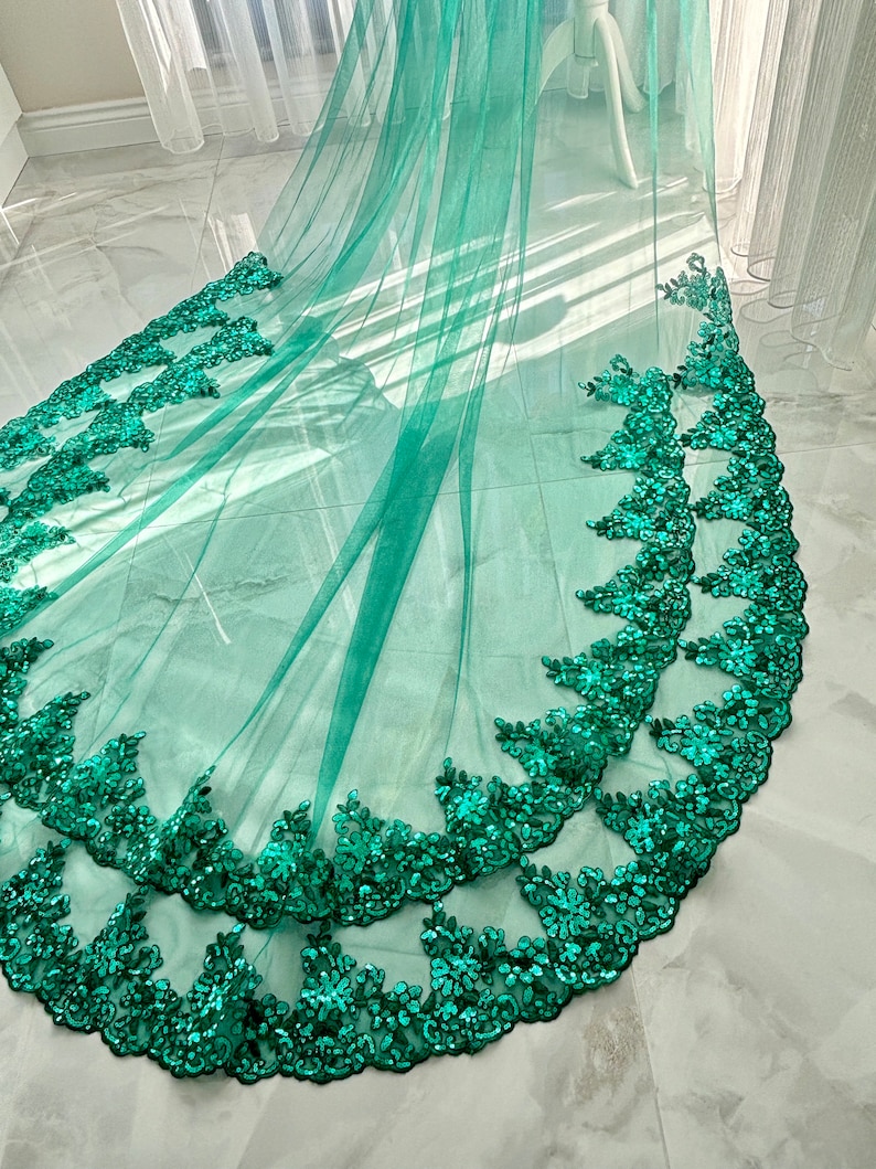 May include: A teal tulle fabric with a double layer of emerald green sequined lace trim.