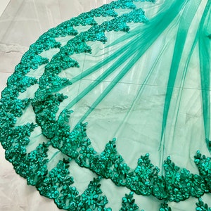 May include: Emerald green tulle fabric with a double layer of sequined lace trim. The lace trim features a floral design.