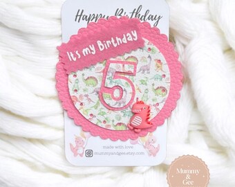 May include: Pink and white birthday card with a dinosaur theme. The card features a large number "5" and the text "It's my Birthday".