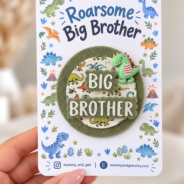 Puede incluir: Una insignia circular con un fondo de fieltro verde y un centro con estampado de dinosaurios con el texto BIG BROTHER. Una pequeña figura de dinosaurio verde está unida a la parte superior. La insignia está en una tarjeta blanca con Roarsome Big Brother.