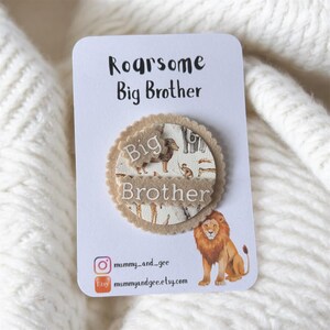 May include: A white card with the text "Roarsome Big Brother" and a circular felt badge. The badge features a lion illustration and the words "Big Brother". The card also includes social media handles and a lion illustration.