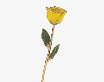 May include: A single yellow rose with a gold-trimmed edge on the petals. The stem and leaves are finished in a metallic gold tone, with the leaves featuring a deep green center. The entire structure has a polished, reflective gold finish throughout.