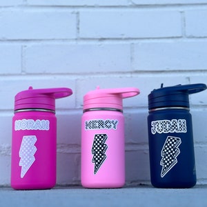 Pu&ograve; includere: Tre borracce in acciaio inox con nomi personalizzati "Norah", "Mercy" e "Judah" in font a scacchi bianco e nero. Ogni bottiglia ha un adesivo a forma di fulmine a scacchi bianco e nero.