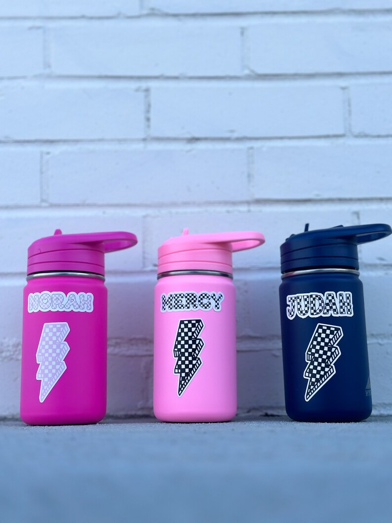 Pu&ograve; includere: Tre borracce in acciaio inox con nomi personalizzati "Norah", "Mercy" e "Judah" in font a scacchi bianco e nero. Ogni bottiglia ha un adesivo a forma di fulmine a scacchi bianco e nero.