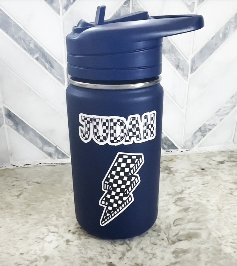 Pu&ograve; includere: Una bottiglia d'acqua blu con un adesivo a forma di fulmine a scacchi bianco e nero e il nome "JUDAH" in lettere a scacchi bianco e nero.