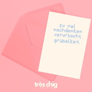 Op de afbeelding: Een lichtroze envelop met een bijpassende kaart. De kaart heeft lichtblauwe tekst met de tekst "Zu viel nachdenken verursacht grübelkeit". De rechter benedenhoek van de afbeelding heeft de tekst "très chig studio".