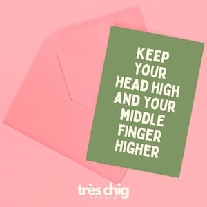Könnte beinhalten: Ein rosa Umschlag mit einer grünen Karte mit dem weißen Text "KEEP YOUR HEAD HIGH AND YOUR MIDDLE FINGER HIGHER". Die Karte und der Umschlag befinden sich auf einem rosa Hintergrund. Die Worte "très chic studio" stehen unten.