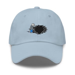 May include: Light blue baseball cap featuring an embroidered design. The design depicts a person looking into a black hole. The person is wearing a gray jacket, blue jeans, and white hair. The cap has a curved brim and a fabric strap.