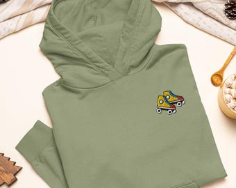 Könnte beinhalten: Ein olivgrüner Kapuzenpullover mit einer Stickerei auf der Brust. Das Motiv zeigt ein Paar gelbe Rollschuhe mit blauen Schnürsenkeln, roten Akzenten und weißen Rollen, die nebeneinander auf dem Stoff abgebildet sind.