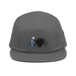 May include: A grey five-panel cap with an embroidered design of a person peering into a black hole. The person is wearing a grey coat and blue trousers. The cap has a flat peak.