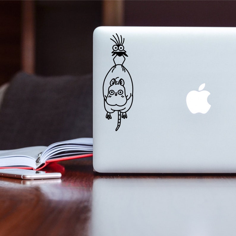 May include: A black and white sticker of a cartoon cat with a bird on its back, applied to a silver laptop.