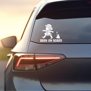 May include: White vinyl car sticker with a cartoon girl carrying a bag and a cat. The sticker says "Baby on Board".