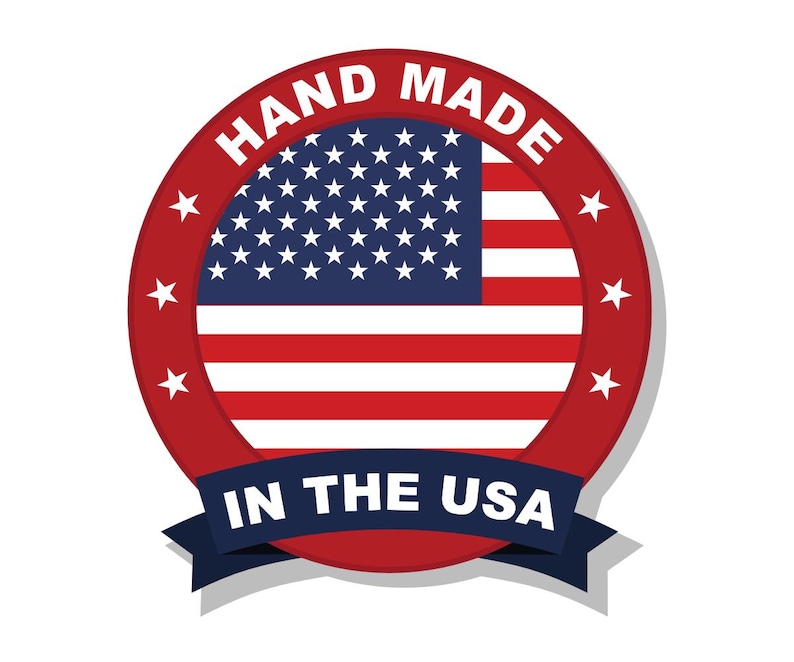 Puede incluir: Un emblema circular con la bandera de los Estados Unidos en el centro. El borde rojo contiene el texto blanco HAND MADE en la parte superior y estrellas blancas a los lados. Una cinta azul oscuro en la parte inferior muestra el texto IN THE USA.