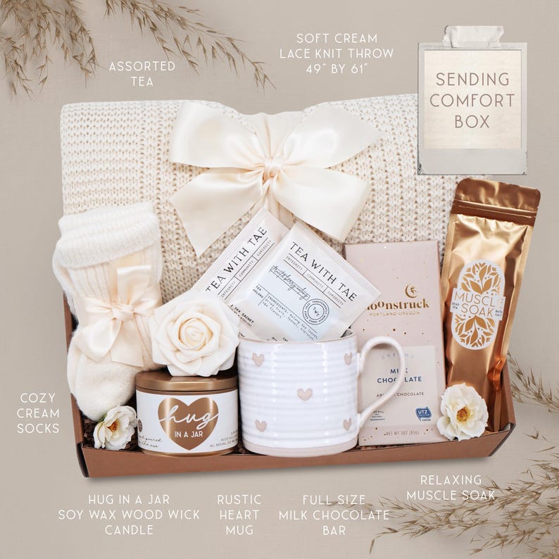 May include: A gift box containing a 49 by 61 inch cream lace knit throw with a satin bow, cream socks, Tea with Tae tea bags, a Hug in a Jar soy candle, a heart-patterned mug, a Moonstruck milk chocolate bar, and a gold pouch of muscle soak.