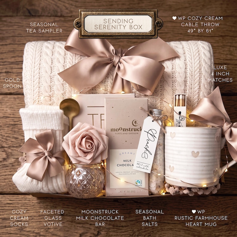May include: A Sending Serenity gift box containing a cream cable knit throw measuring 49 by 61 inches, a gold spoon, white ribbed socks, a faceted glass votive with a faux rose, a Moonstruck milk chocolate bar, bath salts, and a heart mug.