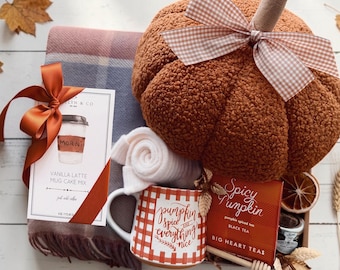 May include: A gift set containing a brown sherpa pumpkin with a gingham bow, a plaid throw blanket, white socks, a mug with red gingham and the text pumpkin spice and everything nice, a vanilla latte mug cake mix, and spicy pumpkin tea.