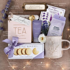 Op de afbeelding: Een geschenkset met het label Soothing Lavender Box, bestaande uit een theesampler, een gouden lepel, lavendelbadzout, een gezichtsmasker, een bodylotion, een manicurekit en een mok met een lavendelmotief.