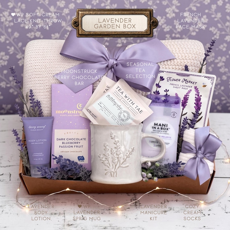 Op de afbeelding: Een Lavender Garden Box cadeaupakket met een cr&egrave;mekleurige kanten gebreide plaid, een Moonstruck pure chocoladereep met bosbes en passievrucht, theezakjes, een mok met lavendelmotief, een gezichtsmasker, bodylotion en een manicure-set.