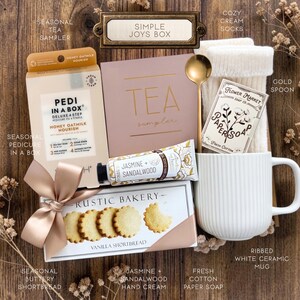 Op de afbeelding: Een geschenkset met een Pedi in a Box honing-havermelkset, een theeproeverijdoos, cr&egrave;mekleurige sokken, een gouden lepel, Flower Market papierzeep, een tube jasmijn- en sandelhout handcr&egrave;me en een doos Rustic Bakery vanille-shortbread koekjes.
