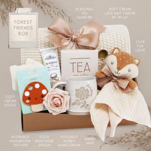 May include: A Forest Friends gift box containing a soft cream lace knit throw measuring 49 inches by 61 inches, a seasonal tea sampler, a tube of coconut honey hand cream, a mushroom silicone teether, a gold demitasse spoon, and a Mama mug.