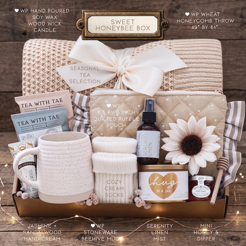 Op de afbeelding: Een Sweet Honeybee geschenkdoos met een 124 bij 155 cm honingraat plaid, een 22 bij 15 cm gewatteerd etui met ruches, een stenen mok, handcr&egrave;me, theezakjes, cr&egrave;mekleurige sokken, linnenspray en een potje honing met een houten dipper.
