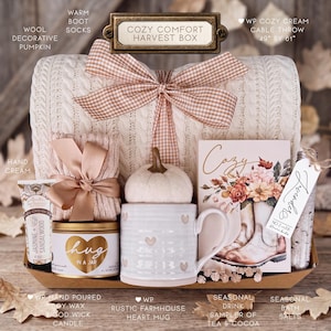 Puede incluir: Un set de regalo Cozy Comfort Harvest Box que incluye una manta de punto trenzado color crema de 124 cm por 155 cm, calcetines, crema de manos, una vela de mecha de madera, una taza con corazones, una calabaza y sales de ba&ntilde;o.