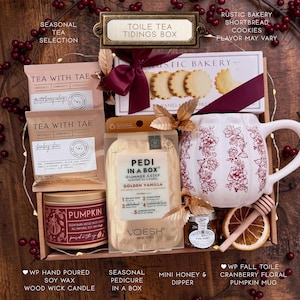 Puede incluir: Una caja de regalo que contiene dos paquetes de t&eacute; Tea With Tae, una caja de galletas de mantequilla Rustic Bakery con cinta granate, un kit de pedicura Voesh, una taza blanca con forma de calabaza y motivos florales rojos, miel, un cuchar&oacute;n y una rodaja de naranja seca.