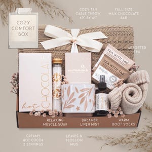 K&ouml;nnte beinhalten: Ein gem&uuml;tlicher Geschenkbox mit Pflegeprodukten. Enth&auml;lt einen beigefarbenen Strickwurf (124cm x 155cm), verschiedene Teesorten, eine Milchschokoladentafel, eine Tasse, Badesalz, Leinen-Mist, warme Stiefelsocken und hei&szlig;e Schokolade.