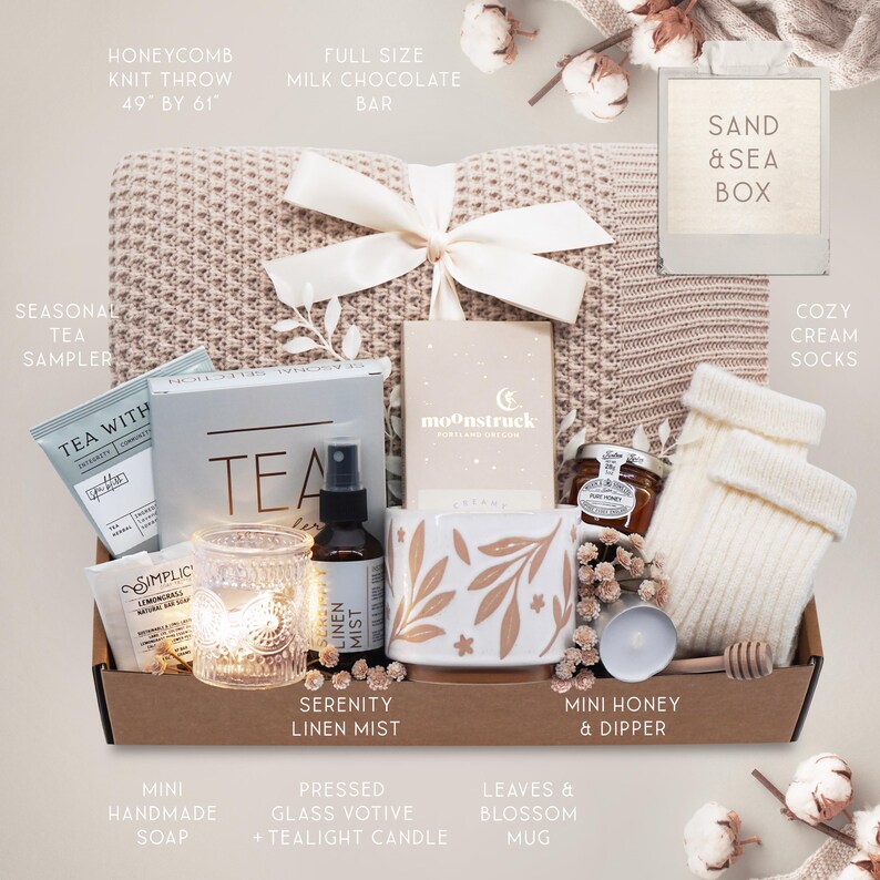 May include: A gift box with a honeycomb knit throw (49" x 61"), tea sampler, mug with leaf design, mini honey, cream socks, and other items. The box includes a full-size milk chocolate bar and a Serenity Linen Mist.