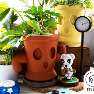 May include: Two terracotta-coloured plant pots with cartoon faces, one with a yellow face and the other with a brown face. A white dog figurine with a guitar is in front of the pots. A black clock with white hands is on a black stand. The text "STL FILE" is on a white background with a grey cube icon.