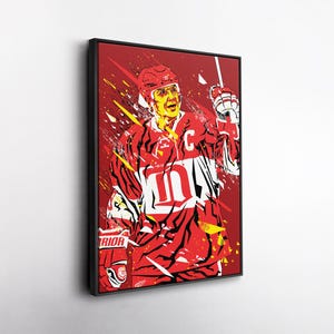 Op de afbeelding: Een ingelijste kunstdruk met een gestileerde illustratie van een hockeyspeler in een rood shirt met nummer 10. Het kunstwerk gebruikt een dynamische, gefragmenteerde stijl met rode, gele en witte accenten tegen een rode achtergrond. De speler draagt een helm en handschoenen.