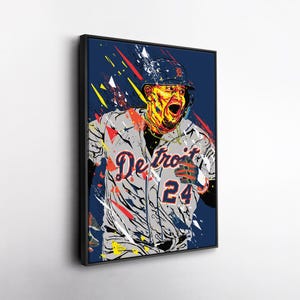 May include: A framed pop art style print of a baseball player in a Detroit Tigers uniform. The player is depicted mid-action with an open mouth, wearing a helmet and jersey with the number 24. The background is navy blue with colorful paint strokes.