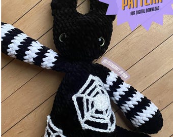 May include: A black Morticia Monster crochet pattern, featuring a plush, horned head, green eyes, and white and black striped arms. The monster has a white spiderweb design on its chest and legs. The image includes text that says "Morticia Monster Crochet Pattern PDF Digital Download."