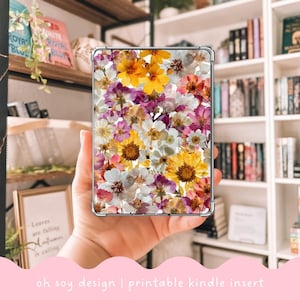 Può includere: Inserto trasparente per custodia Kindle con un vivace design floreale. L'inserto presenta un collage di fiori pressati colorati nelle tonalità del giallo, bianco, rosa e viola. Il testo "oh soy design | printable kindle insert" è visibile in basso.