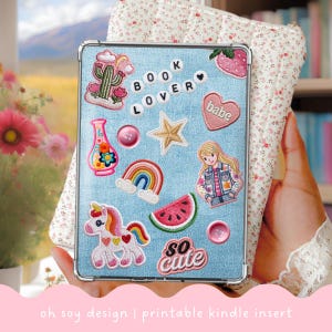 May include: A light blue Kindle case decorated with embroidered patches, including a cactus, rainbow, unicorn, and watermelon. The case has the words "BOOK LOVER" and "so cute" on it. The text "oh soy design | printable kindle insert" is at the bottom.