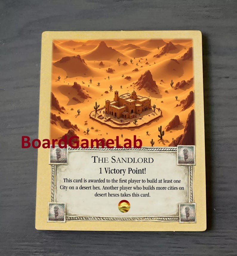 Peut inclure: Une carte beige avec une sc&egrave;ne de d&eacute;sert et un b&acirc;timent au centre. Le texte sur la carte indique "The Sandlord 1 Victory Point! This card is awarded to the first player to build at least one City on a desert hex. Another player who builds more cities on desert hexes takes this card."
