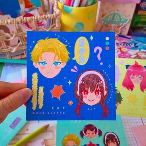 May include: A blue background with a grid pattern features cartoon character stickers. The stickers include a blonde male character with blue eyes, a female character with brown hair and red eyes, a star, a flower, and a speech bubble with the word "SPY" in it. The text "twilight" and "thorn princess" are also included. The text "@danizushop" is at the bottom of the image.