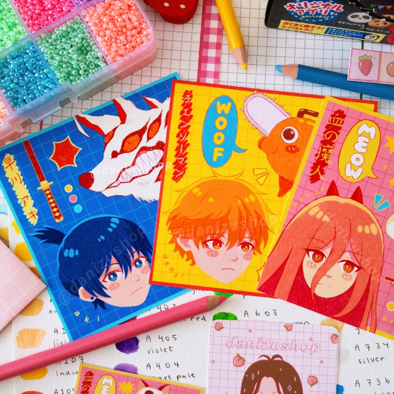 May include: Four colorful stickers featuring anime characters with Japanese text. The stickers are on a white background with a grid pattern. The characters are a blue-haired boy with a sword, an orange-haired boy with a chainsaw, a pink-haired girl with a red devil horn, and a white wolf with red eyes.