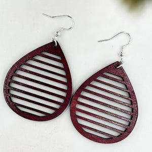 May include: A pair of maroon wood earrings with a geometric design. The earrings are shaped like teardrops and have a silver hook.