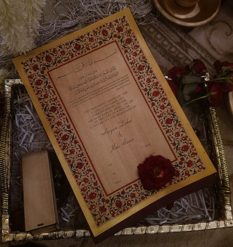 Puede incluir: Un certificado de matrimonio marr&oacute;n y dorado con bordes florales ornamentados. El texto dice "Este acuerdo hecho el 31 de octubre de 2021 correspondiente al 14&ordm; d&iacute;a de Rabi Al-Awal, 1442 AH en la ciudad de Karachi certifica el matrimonio de Shayan Zahid y Hoha Aamir".