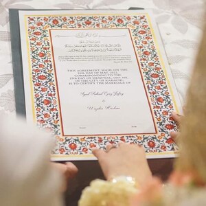 Puede incluir: Un certificado de matrimonio con un borde floral adornado en rojo, amarillo y verde. El texto dice "Este acuerdo, hecho el 28 de mayo de 2022, correspondiente al 27 de Shawwal, 1443 AH, en la ciudad de Karachi, certifica el matrimonio de Syed Fahad Ejaz Jafry y Wajiha Hashme."