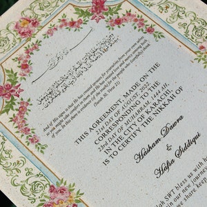 Puede incluir: Un certificado de boda decorativo con bordes florales y caligraf&iacute;a. El texto dice "Este acuerdo, hecho el 21 de agosto de 2022, correspondiente al 23&ordm; d&iacute;a de Muharram 1444 AH, en la ciudad de Karachi, certifica el Nikkah de Hasham Dawra y Hafsa Siddiqui. Que Allah SWT nos bendiga con felicidad mientras comenzamos nuestro nuevo viaje juntos. El amor que compartimos nos mantiene unidos."