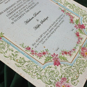 Puede incluir: Un certificado de matrimonio blanco y azul con un borde floral. El texto dice "Este acuerdo hecho el 21 de agosto de 20... correspondiente al 23 d&iacute;a de Muharram, 1444 AH. En la ciudad de Karachi, certifica el Nikkah de Hasham Dawra & Hafsa Siddiqui. Que Allah SWT nos bendiga con salud y felicidad al comenzar nuestro nuevo viaje juntos y que el amor que compartimos siga creciendo cada d&iacute;a."