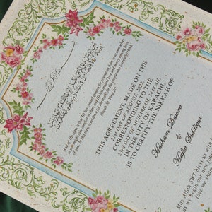 Puede incluir: Un documento decorativo con bordes florales y caligraf&iacute;a en escritura &aacute;rabe. El texto incluye la fecha 21 de agosto de 2022 y los nombres Hasham Dawra y Hafsa Siddiqui. El documento es un certificado de matrimonio.
