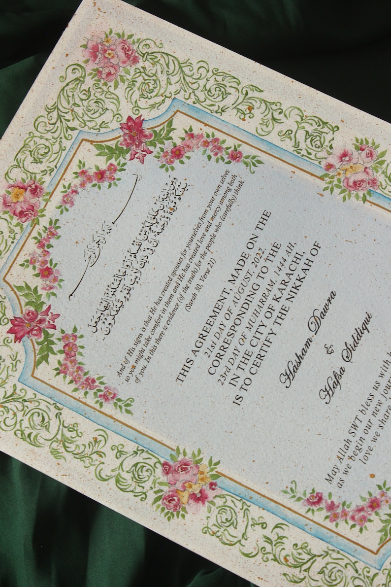 Puede incluir: Un documento decorativo con bordes florales y caligraf&iacute;a en escritura &aacute;rabe. El texto incluye la fecha 21 de agosto de 2022 y los nombres Hasham Dawra y Hafsa Siddiqui. El documento es un certificado de matrimonio.