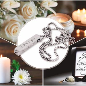 May include: Silver necklace with a rectangular pendant engraved with "I love you 08.14.2011". The necklace is displayed on a white background with white roses and candles.