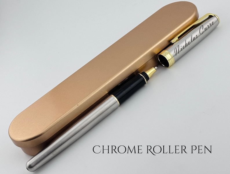 May include: A chrome roller pen with a gold-colored cap and trim, and a matching pen case. The pen is silver with black accents and the name "Nicholas Curro" is engraved on the side. The text "CHROME ROLLER PEN" is below the pen.