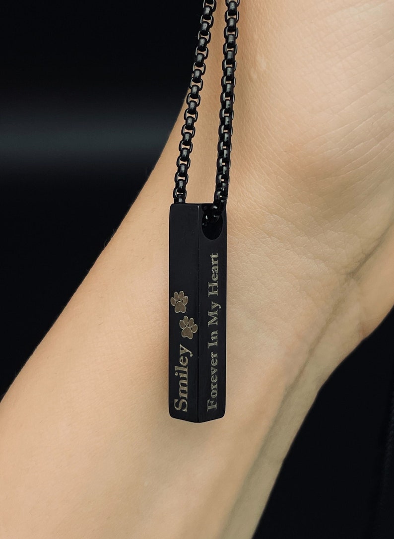 May include: Black chain necklace with a black rectangular pendant engraved with "Smiley Forever In My Heart" and two paw prints.