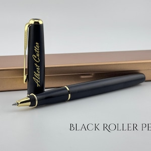 May include: A black roller pen with gold accents and a matching pen case. The pen's cap is open, revealing the pen's tip. The cap has the name "Albert Cutter" in gold lettering. The pen case is a metallic gold color.