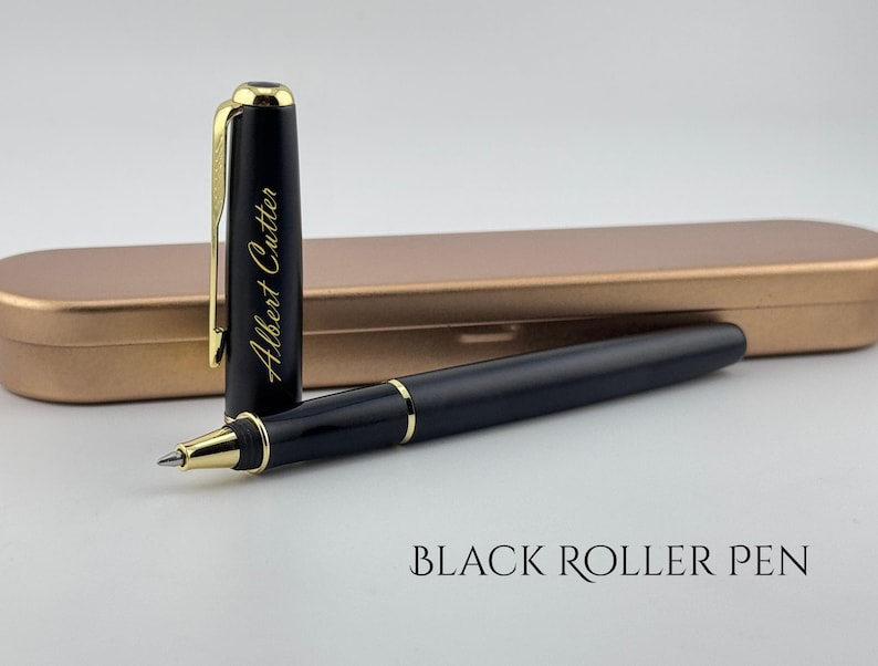 May include: A black roller pen with gold accents and a matching pen case. The pen's cap is open, revealing the pen's tip. The cap has the name "Albert Cutter" in gold lettering. The pen case is a metallic gold color.